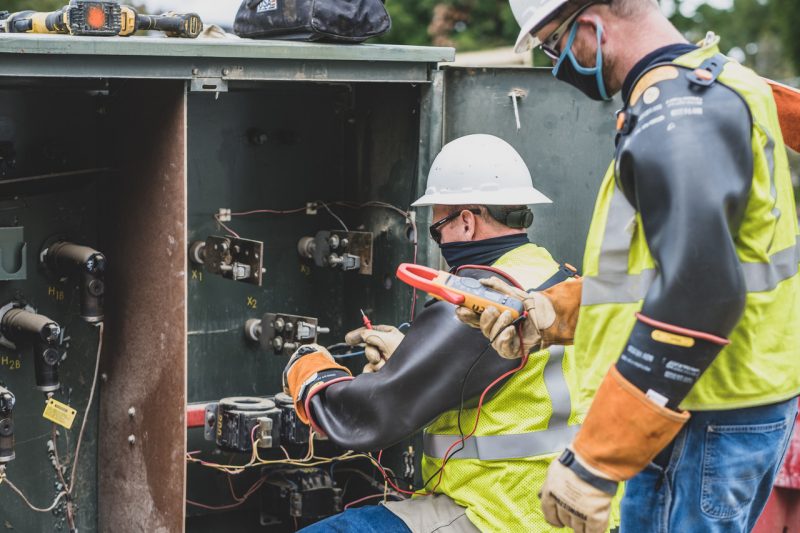 utility workers working on a large outdoor fuse box